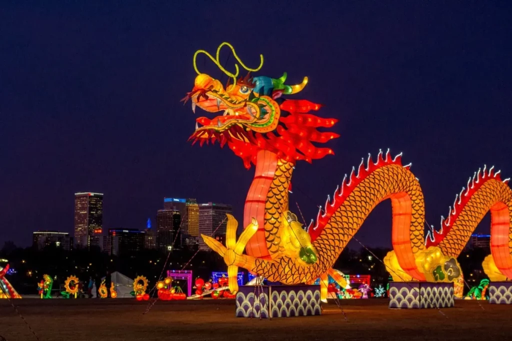 Ano-Novo Chinês, lanterna de dragão gigante, colorida e iluminada, com arranha-céus ao fundo à noite.