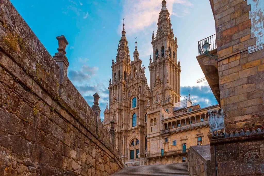 Vista da fachada da Catedral de Santiago de Compostela, com suas torres e escadaria de pedra, ao final do Caminho de Santiago.