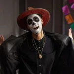 Dia dos Mortos, homem jovem com maquiagem de caveira "La Catrina" e chapéu, com a boca aberta em celebração.
