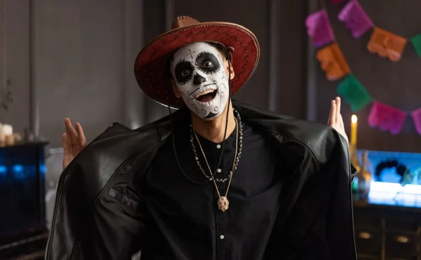 Dia dos Mortos, homem jovem com maquiagem de caveira "La Catrina" e chapéu, com a boca aberta em celebração.