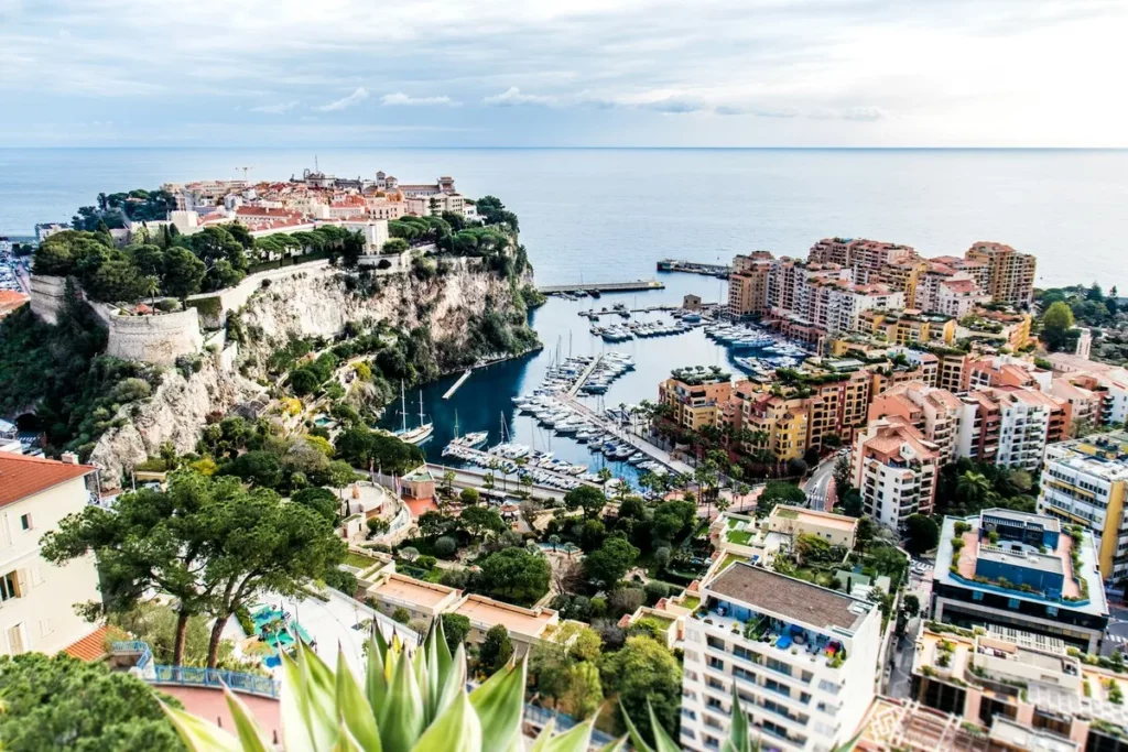 Vista panorâmica de Mônaco na Europa, mostrando o Rochedo com a cidade murada, o porto cheio de iates e edifícios modernos à beira-mar.