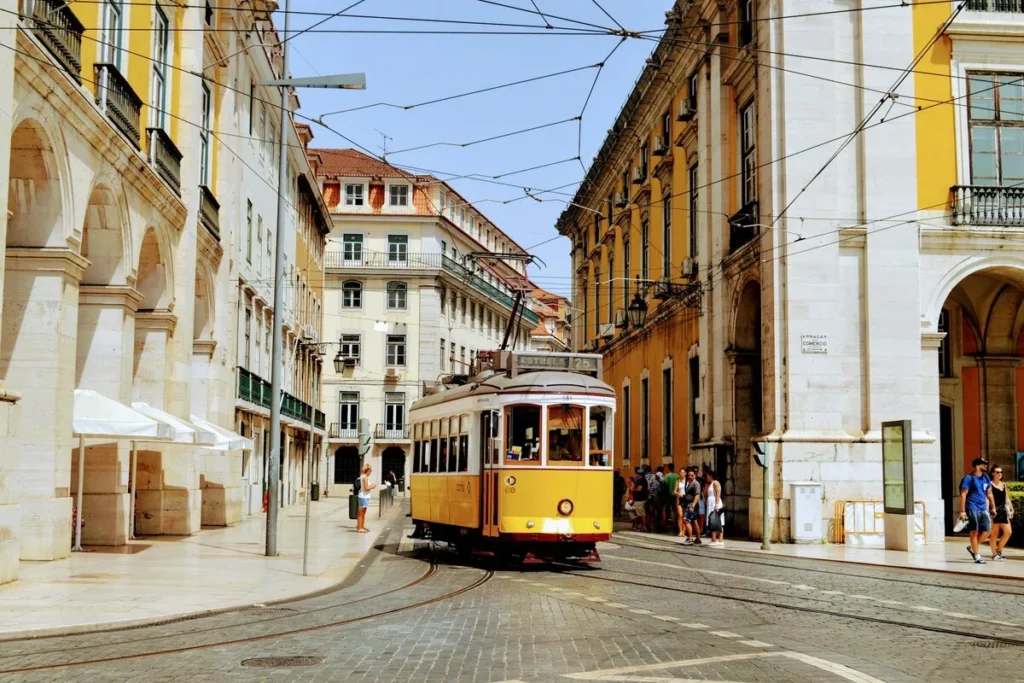 Dicas de viagem para Lisboa, com o famoso elétrico amarelo na rua do bairro histórico.