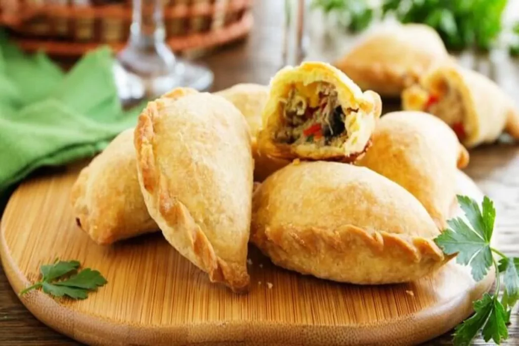 Empanadas recém-assadas, com uma delas aberta, mostrando o recheio de carne e a massa crocante, como a empanada argentina.