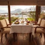 Gastronomia em viagem: guia completo de sabores e experiências Mesa de restaurante posta com vista para o mar, simbolizando a experiência de gastronomia de luxo.