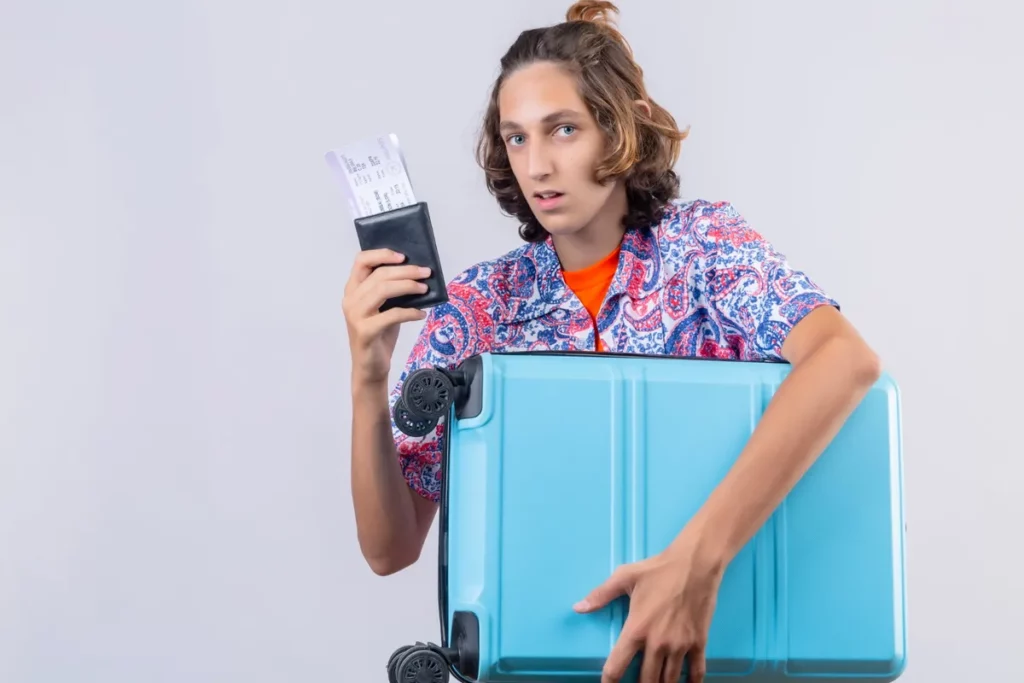 Jovem segurando passagens e uma mala de viagem azul com expressão de preocupação, ilustrando perrengues comuns em viagens.