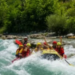 Experimente rafting: aventura, relaxamento e recarga de energia Grupo de pessoas praticando rafting em corredeiras, usando coletes salva-vidas e capacetes coloridos em bote inflável amarelo.