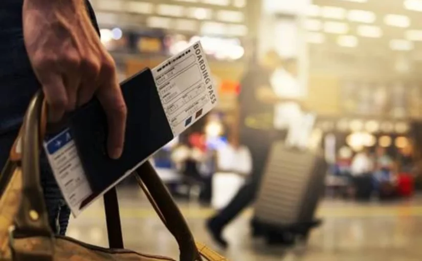 Passageiro segurando passaporte e cartão de embarque no aeroporto, representando viagens low cost e passagens aéreas econômicas.