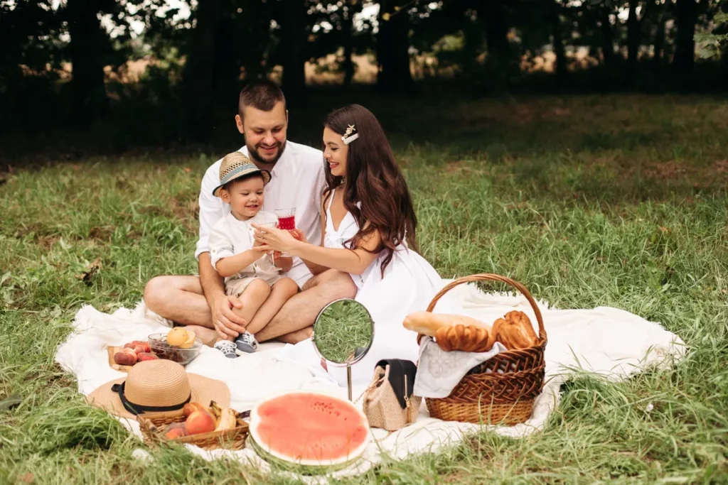Família feliz desfrutando de um dos muitos piqueniques ao ar livre, com frutas e bebidas.