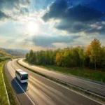 Ônibus de viagem em estrada cercada por árvores e céu ensolarado.