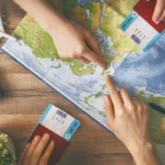 Mapa do mundo em cima de uma mesa com duas mãos apontando para ele