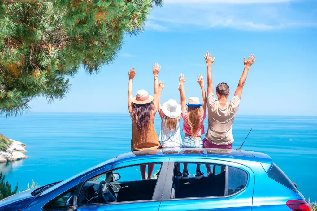 Família encostada no carro, levantando os braços