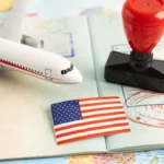 passaporte aberto com carimbo de viagem ao lado de miniatura de avião e bandeira dos estados unidos