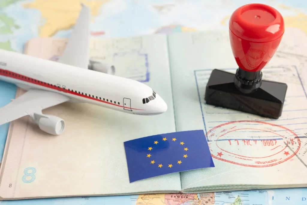 passaporte aberto com carimbo de entrada ao lado de miniatura de avião e selo de viagem